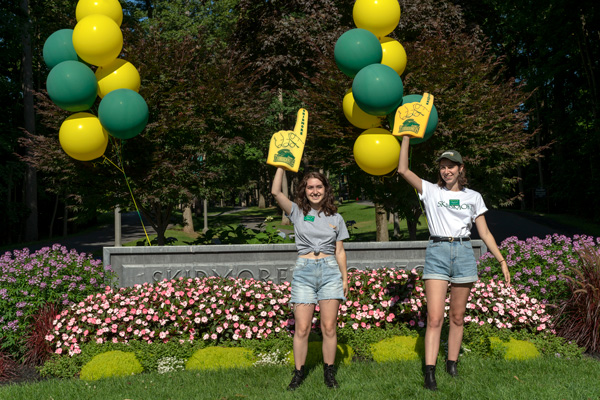 Two student stand by the ¼ϲʿ welcome sign 