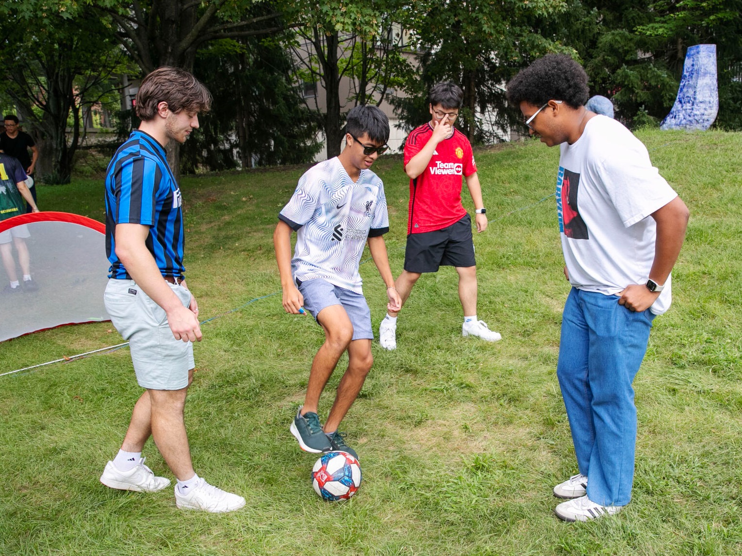 Four students play soccer on ¼ϲʿ's South Lawn.